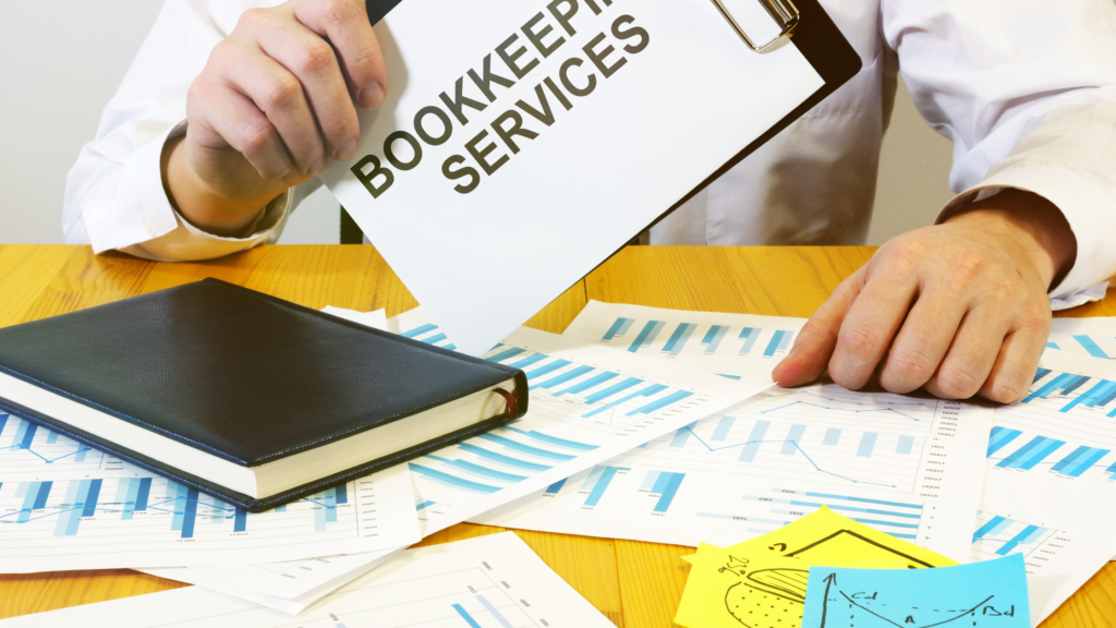 Businessman reviewing charts and documents labeled “Bookkeeping Services.”