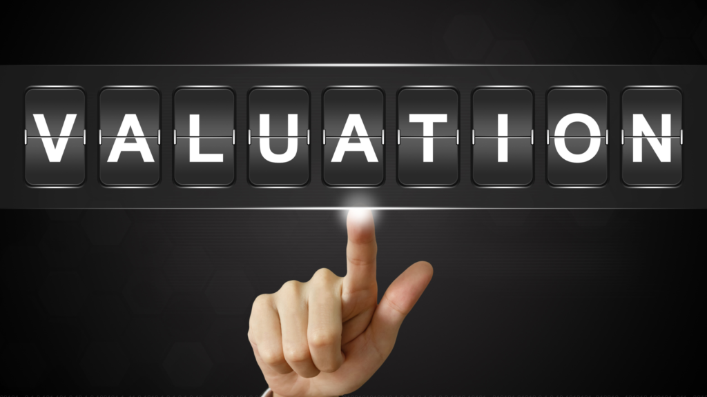Finger pressing illuminated digital flipboard displaying the word “Valuation,” representing financial evaluation.
