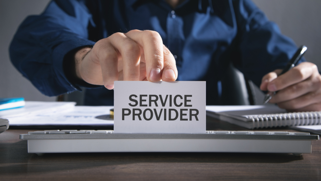 Businessperson holding a card labeled “Service Provider” while working at a desk.
